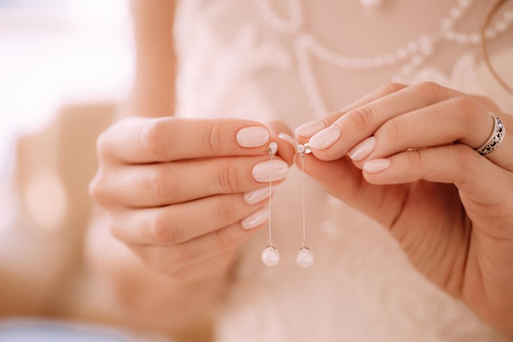 Close up of womans hands holding her recently found pearl earrings