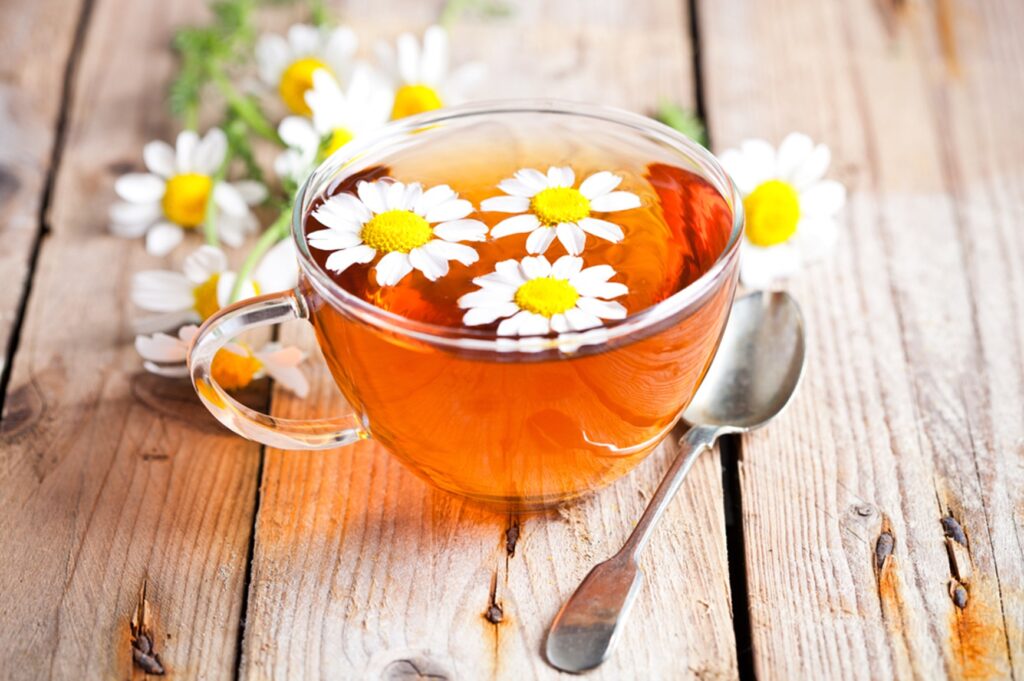 Glass of Honey chamomile tea latte with decorative daisies