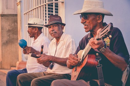 Group of three Cuban men playing instruments and sitting together