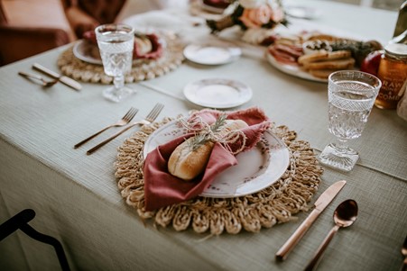 Photograph of a homemade rosemary mini baguette on a wicker plate decorated with pink cloth
