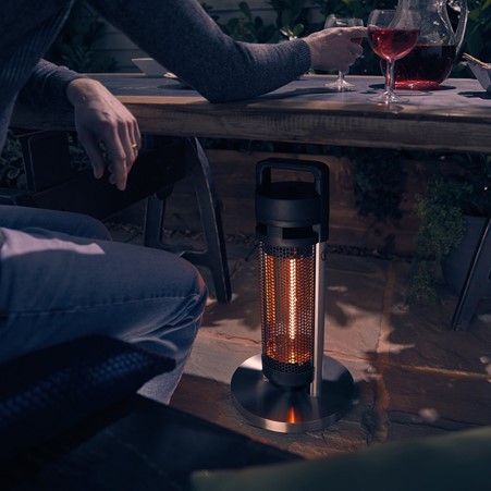 Photograph of two adults sitting at a patio table next to a Swan Portable Patio Heater