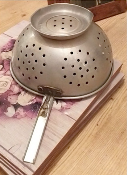 Photograph of old swan colander upside down on a wooden table