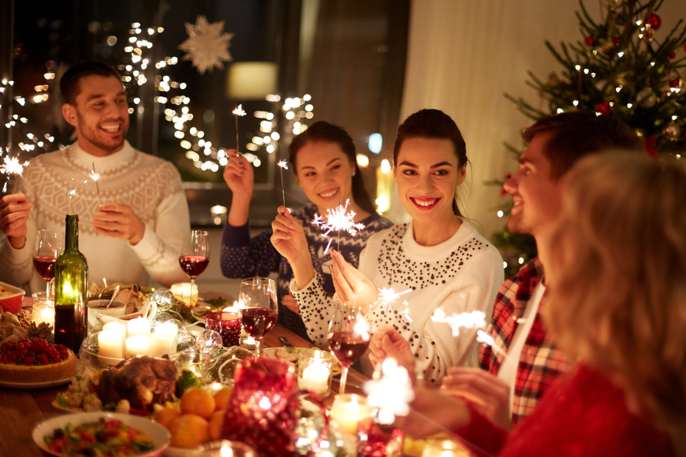 Photograph of a family at christmas time sat at the table holding sparklers