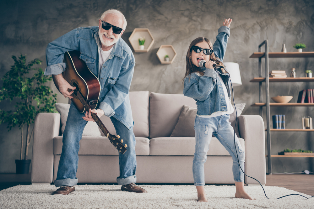 Photograph of a grand father and grand daughter playing a guitar and singing