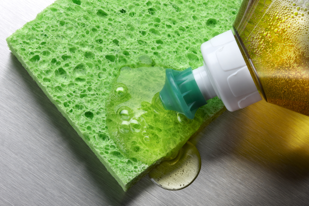 Photograph of washing up liquid being applied to a green sponge