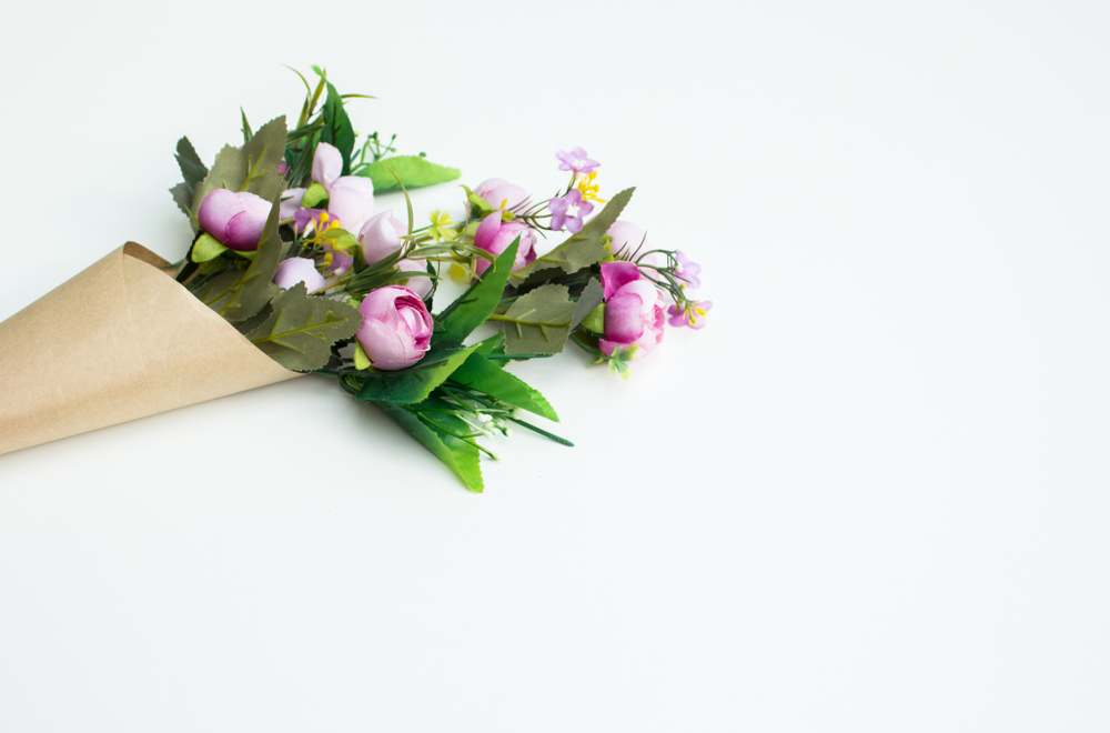 Colour image of a bouquet of pink and white flowers wrapped in brown paper