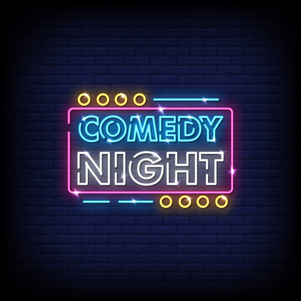 Image of a neon sign on a dark wall saying comedy night