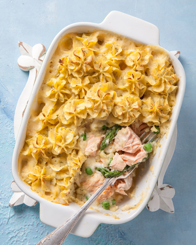 Image of a casserole dish with fish pie in, with salmon, peas and piped potato topping