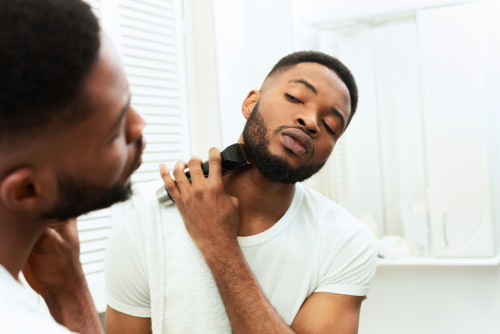 Image of a young man grooming his beard with a beard trimmer