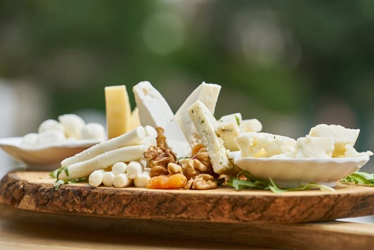 Cheeseboard of assorted cheeses and walnuts resting on a thin layer of rocket