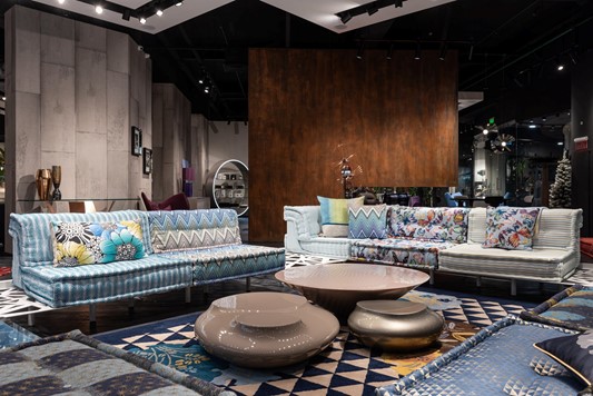 Maximalist interior design with blue and white couches, spherical brown tables, large abstract rug and marble walls