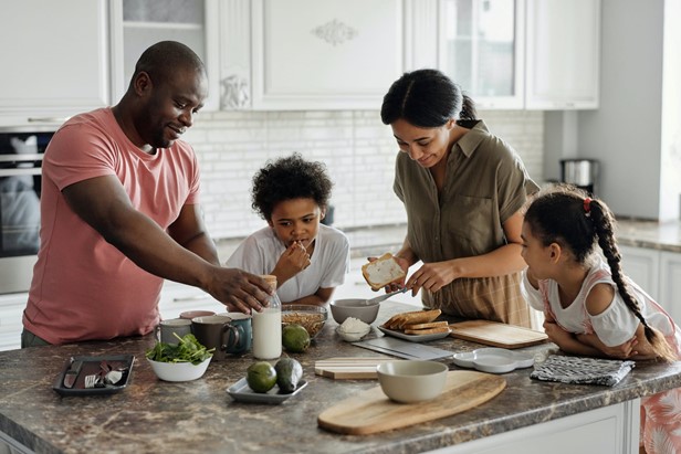 Photo of a family making breakfast at their marbled island in the middle of a tiled white kitchen