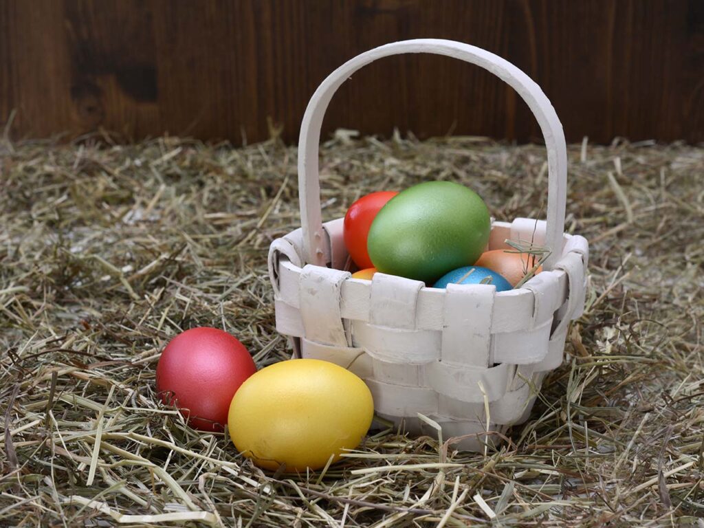 Small white wooden basket with coloured stained easter eggs inside