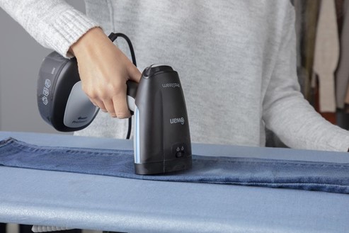 Photograph of father using the Swan Portable Garment Steamer to steam a pair of blue jeans