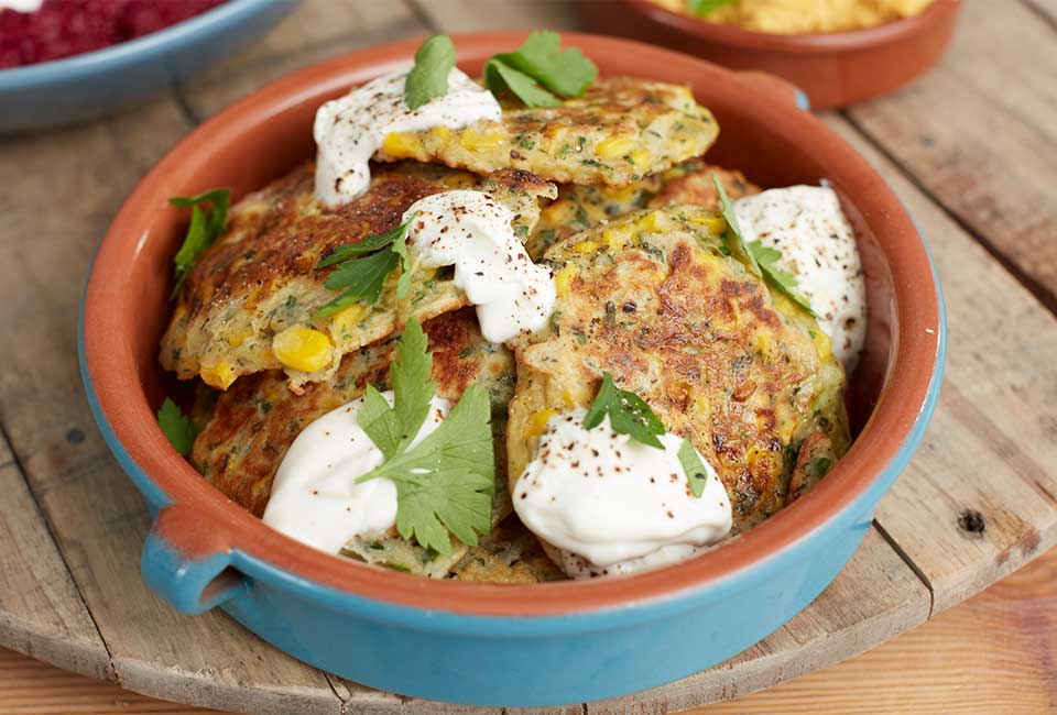 Photograph of spinach and sweetcorn fritters in a blue bowl