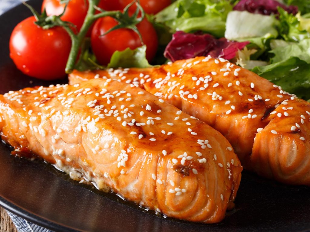 Steamed salmon with salad and tomatoes on a black plate