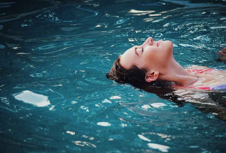 Woman swimming in a blue pool on her back