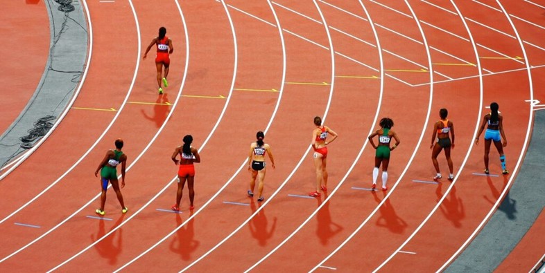 Female sprinters from different countries on a red running track at the London 2012 Olympic Games