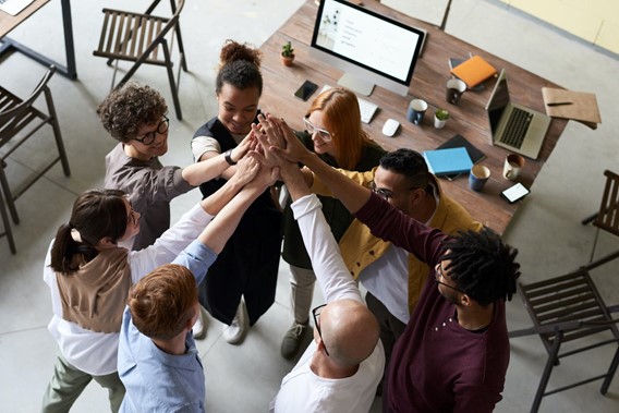 Overhead view of a diverse group of young people high fiving in an office space