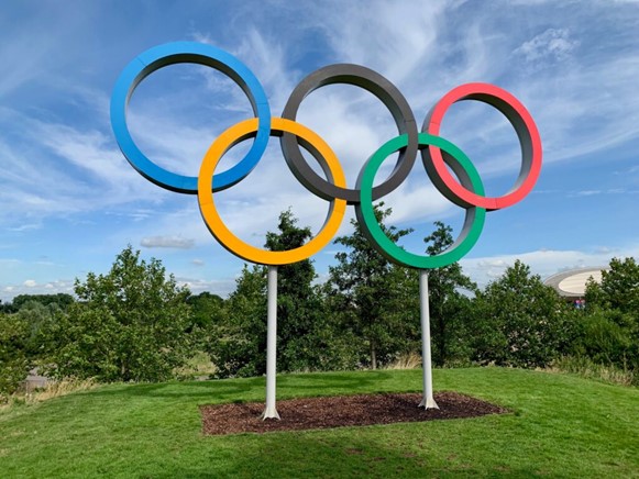 Statue of the olympic rings in different colours on a green hill