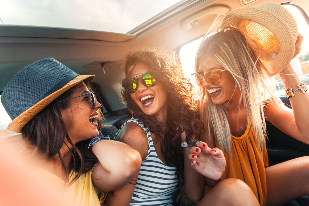 Group of three female friends bonding for National Girlfriends Day by going on a road trip