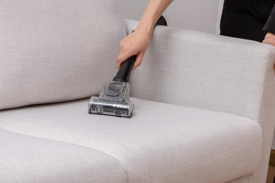 Close up of Petmaster tool vacuuming over a cream coloured sofa.