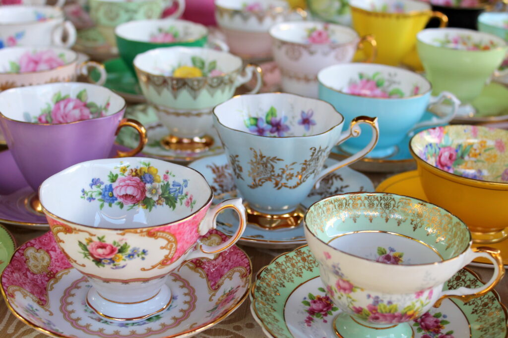 Rows of pastel-coloured floral patterned teacups and saucers lined up. 
