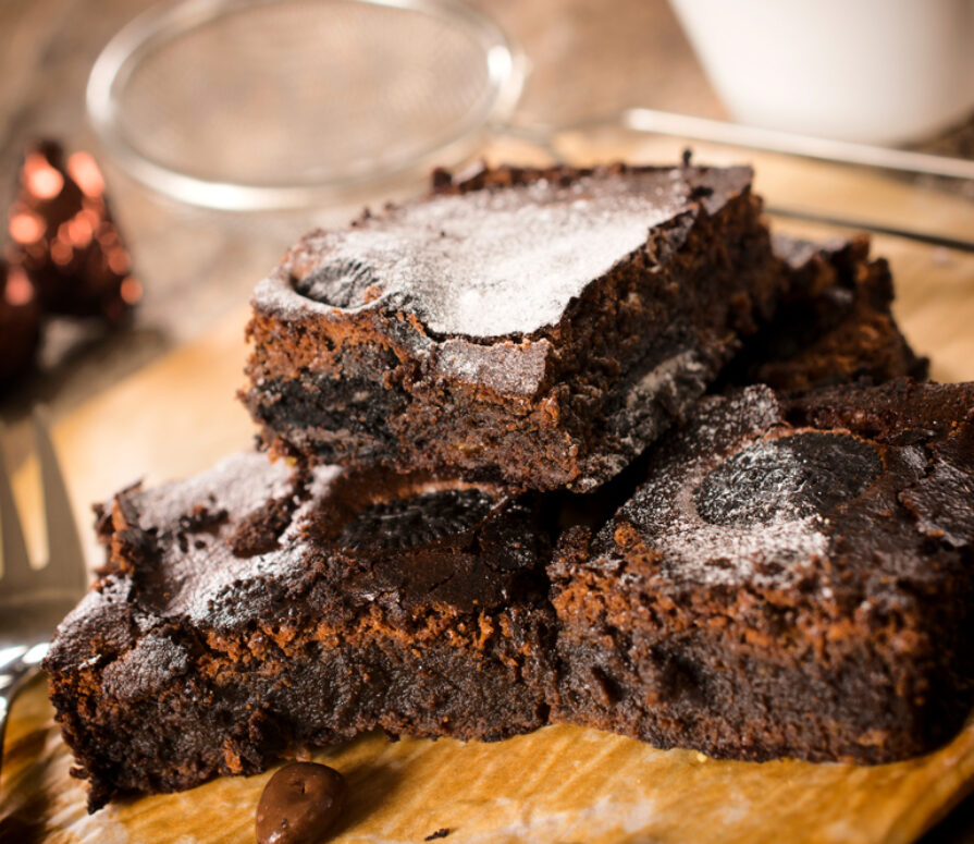 A close-up image of chocolate brownies topped with flour.