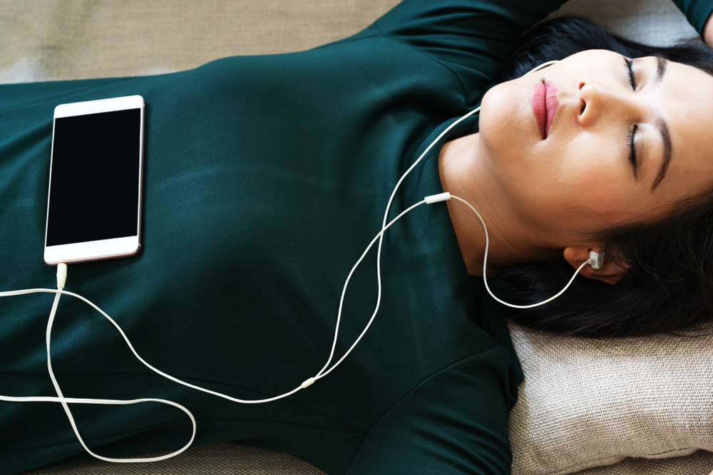Over head view of woman relaxing and listening to music on her phone