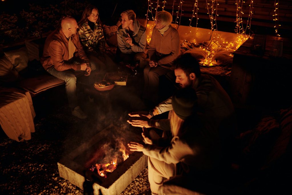 A selection of friends sitting by a fireplace to warm themselves up. 