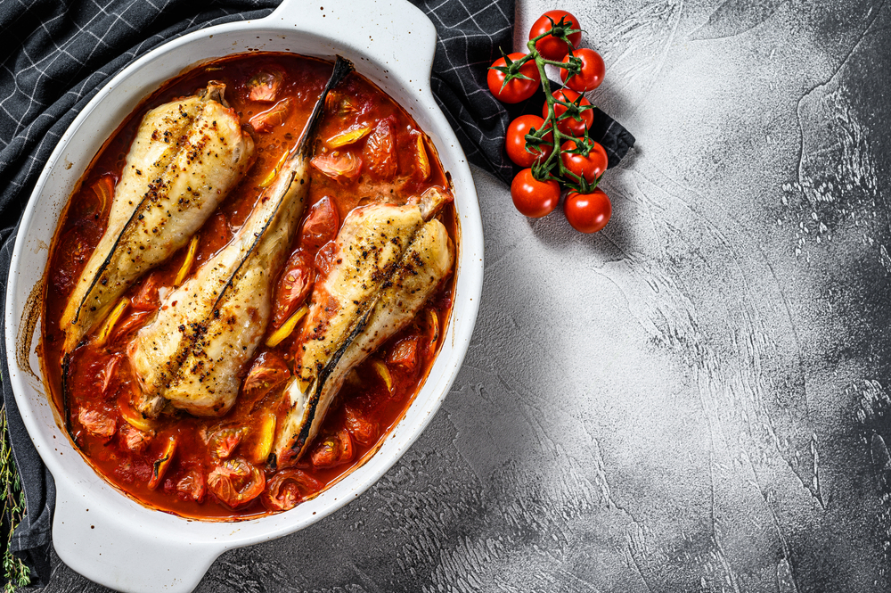 Grilled monkfish in a white ceramic pot in red tomato sauce
