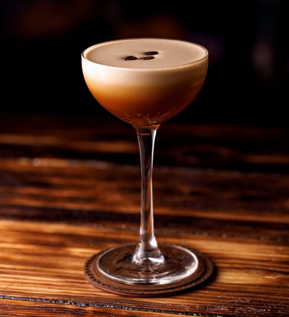 A stunning coffee liqueur cocktail sitting on a smoked table