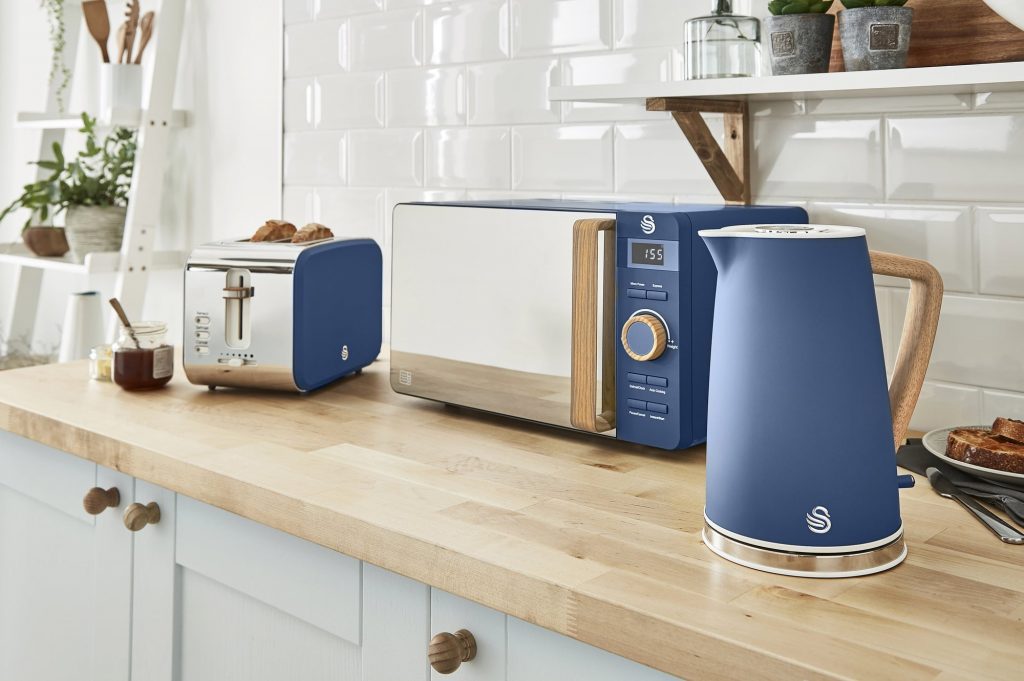 Blue nordic kettle, microwave and 4 slice toaster on a rustic kitchen counter