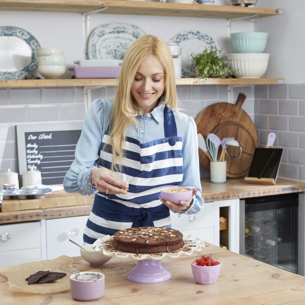 Fearne Cotton decorating a cake, resting on the Fearne by Swan Range cake stand, with almonds