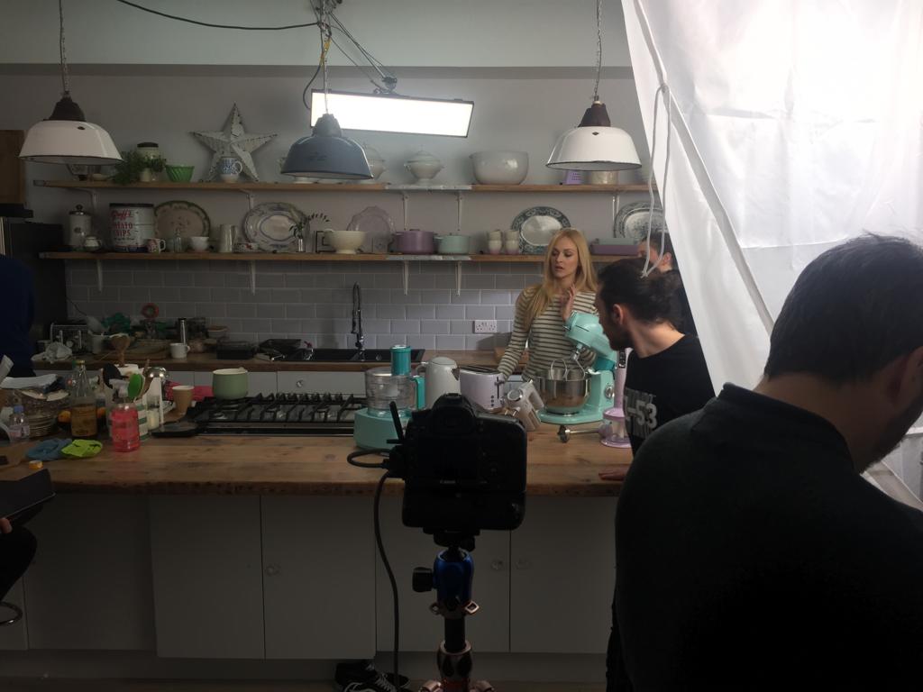 Photograph of Fearne Cotton on the set for the Fearne by Swan range trailer shoot, with Fearne by Swan kettles and baking equipment in the background