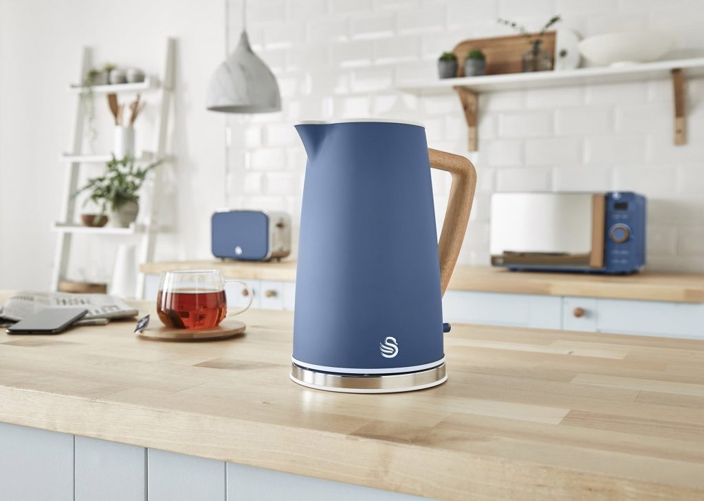 Swan Nordic Blue Kettle on a wooden ash kitchen counter next to a small glass of black tea