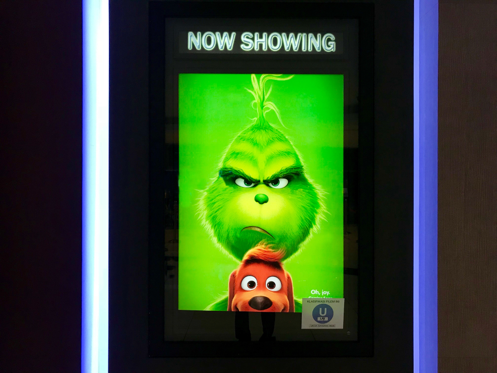 Colour image of new Grinch movie poster on a phone screen saying now showing