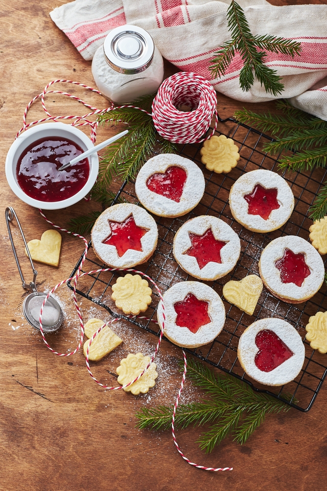 image of christmas jam sandwich cookies on a table surrounded by fir tree branches