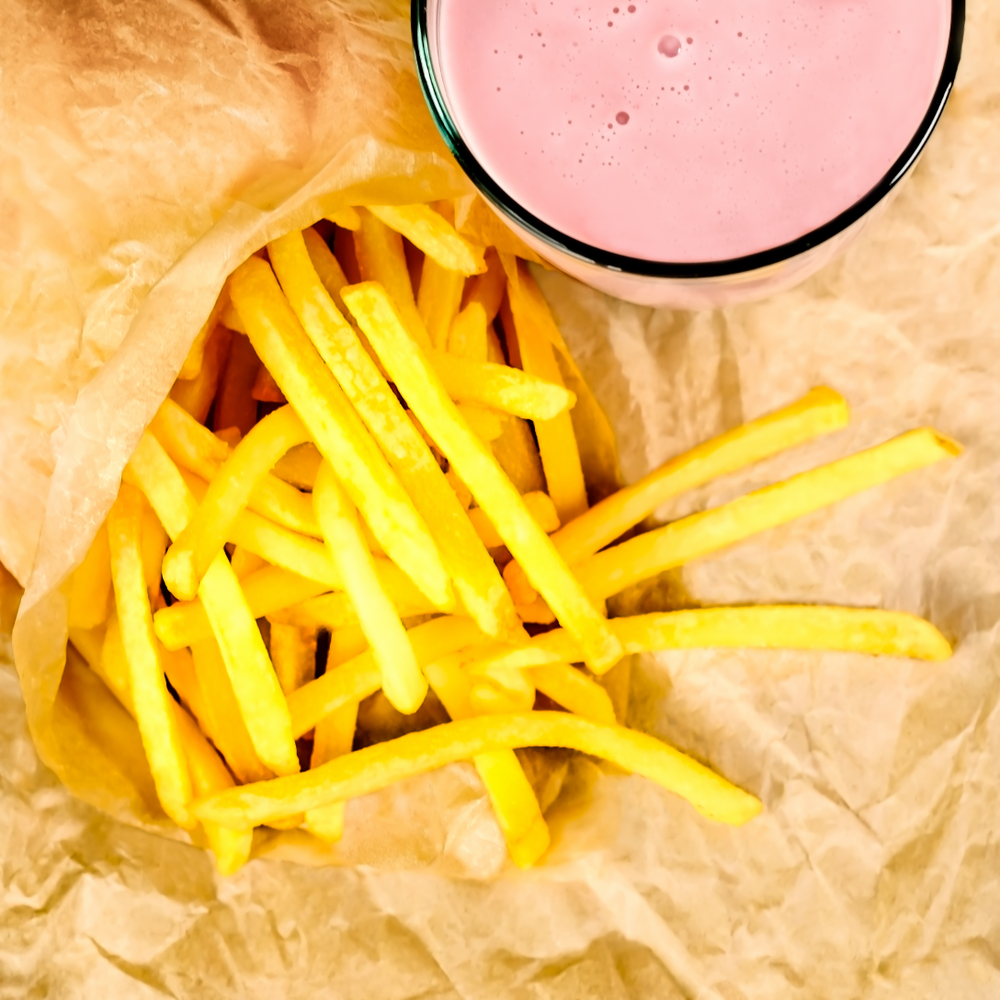 Birdseye photo of a strawberry milkshake next to a side of fries