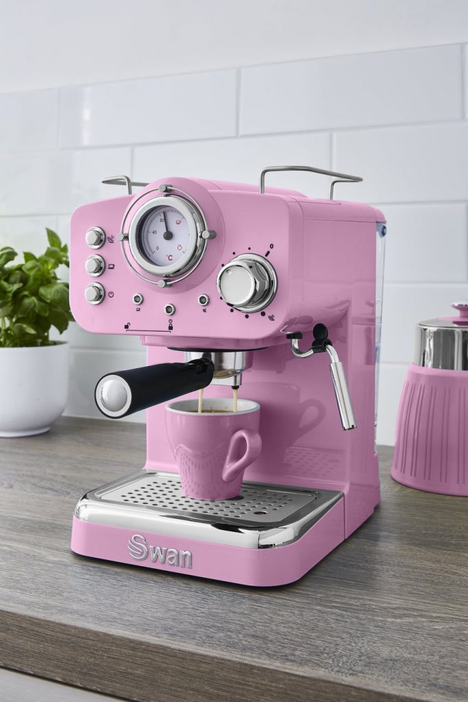 Lifestyle image of the Swan Retro pump espresso coffee machine in pink making an espresso in a matching pink cup