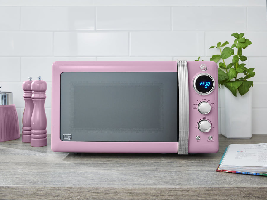 Colour image of the Swan Retro Digital LED microwave on a kitchen countertop next to the Swan Retro salt and pepper mills. 