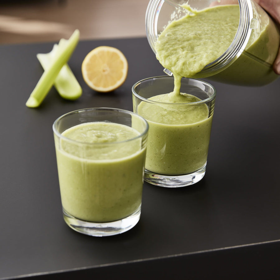 Image of two glasses with a green smoothie inside. One glass is being filled up from the Swan Stealth Blender. 