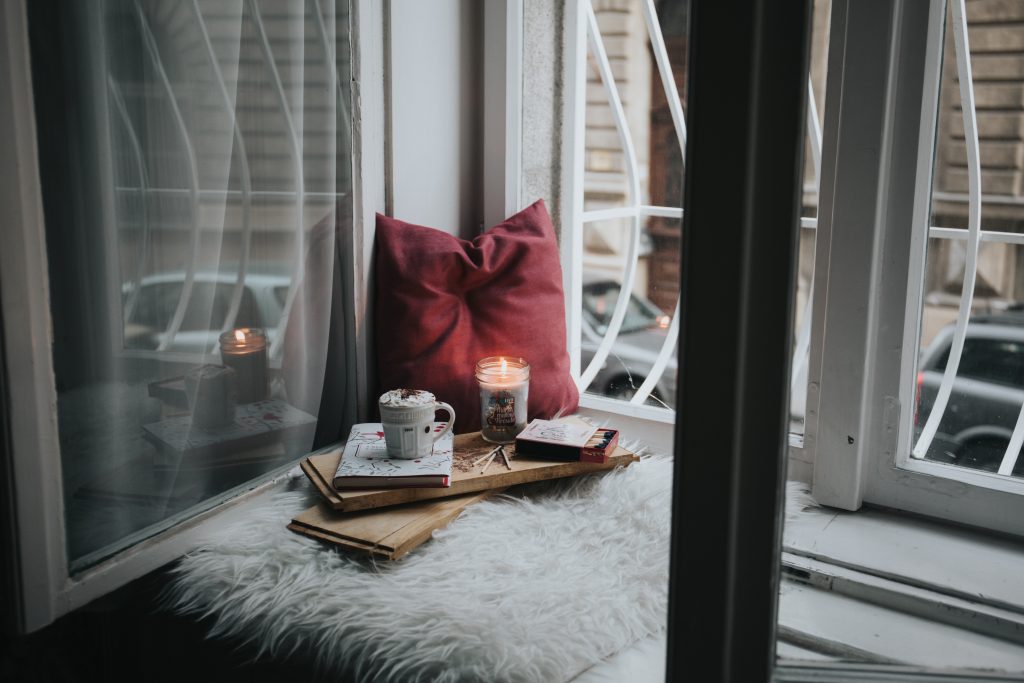 A windowsill area with candles, books and a cup of tea.